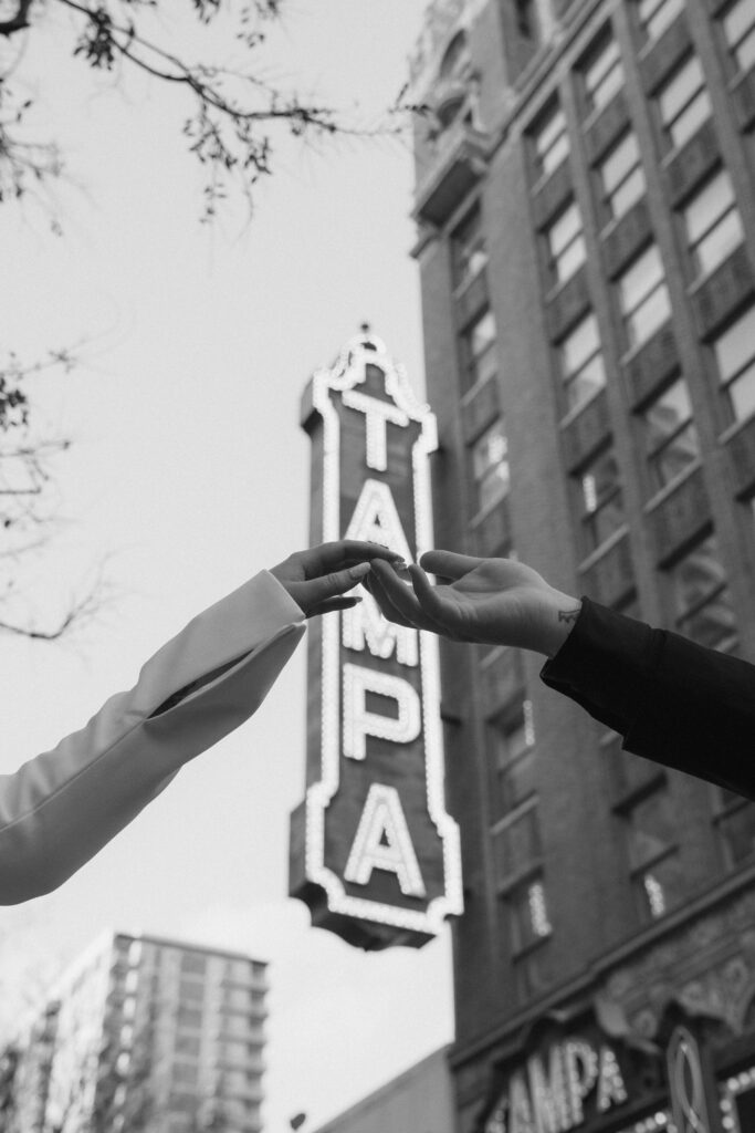 a detail shot of a couple holding hands with the Tampa Theatre sign in the background