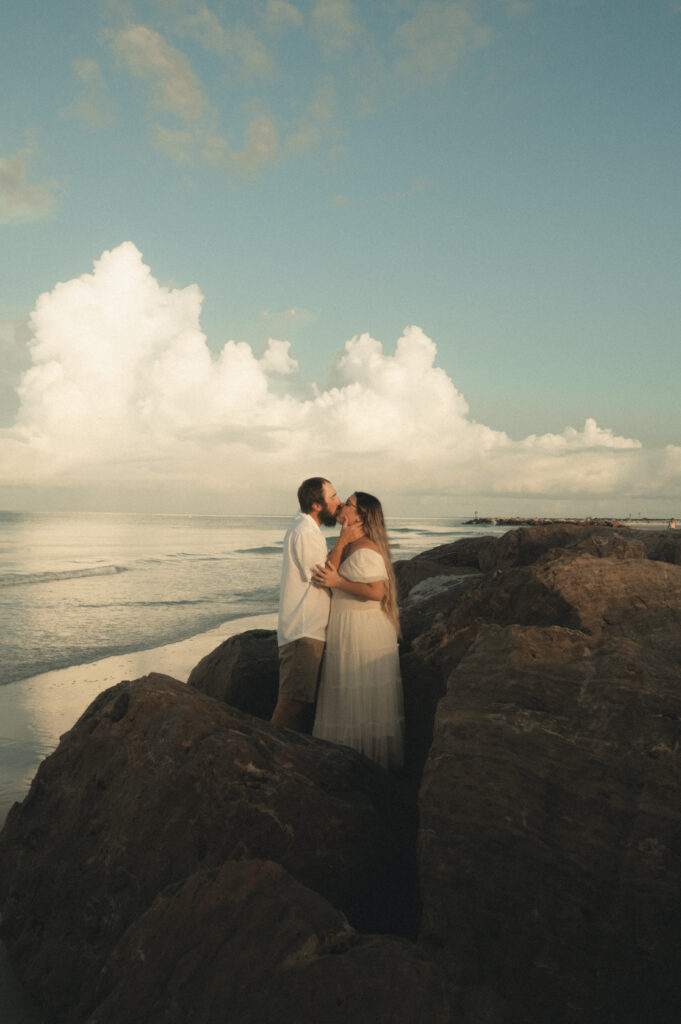 a couple kissing among the rocks at Upham beach during their St. Petersburg engagement photos