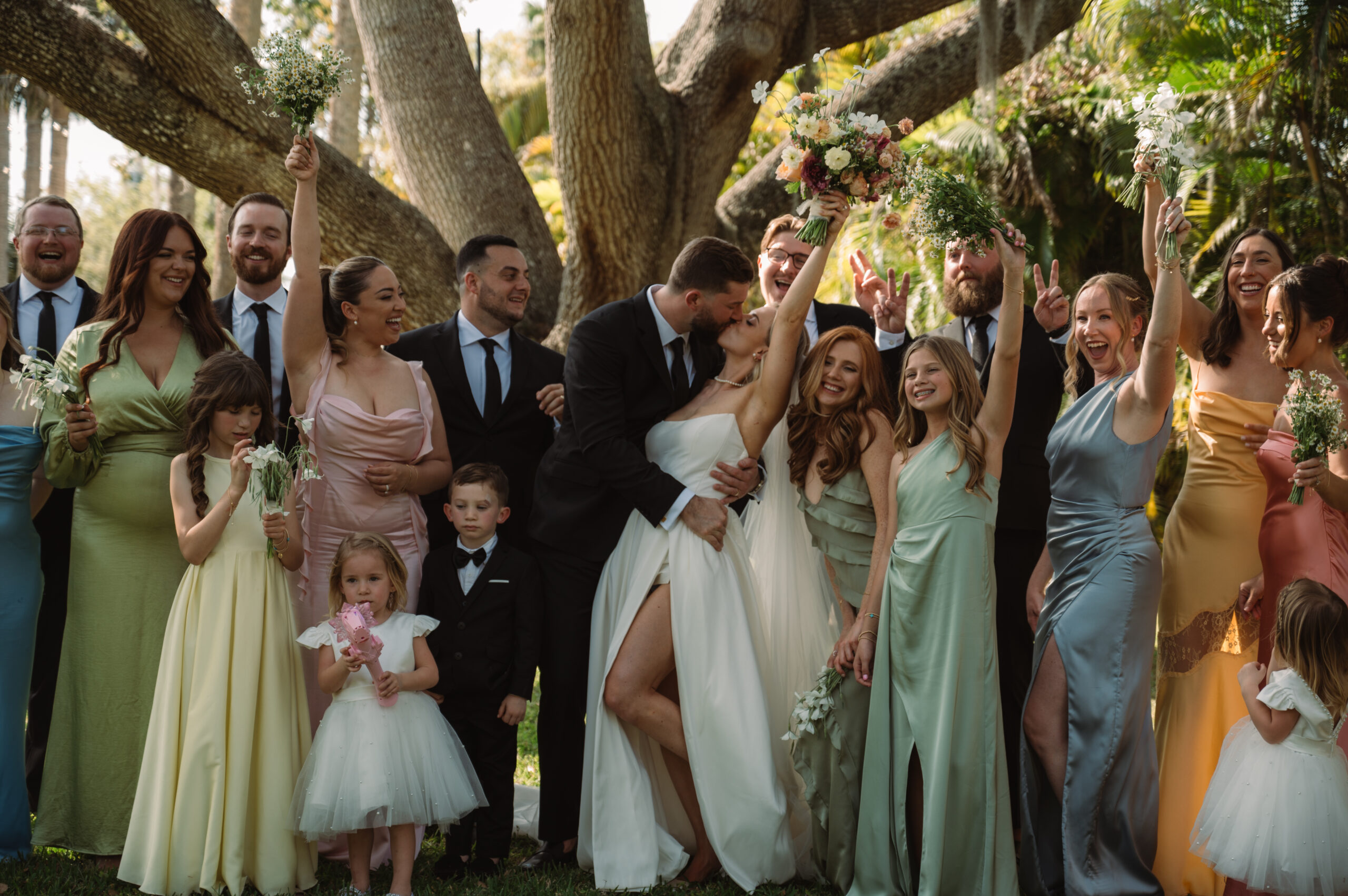 bride and groom kiss as their wedding party cheers around them