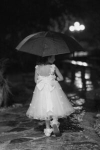 documentary photo of a flower girl walking in the rain with an umbrella