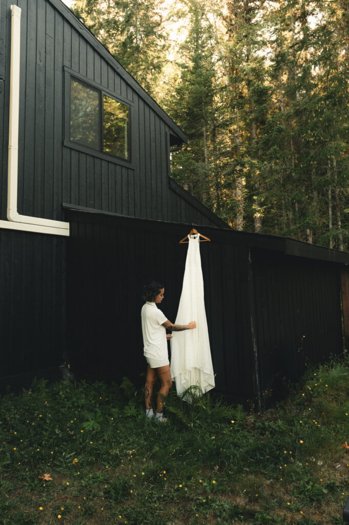 a bride admiring her wedding dress as it hangs elegantly 