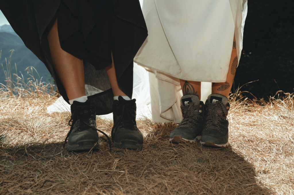 a shot of two brides legs, highlighting their hiking boots under their dresses