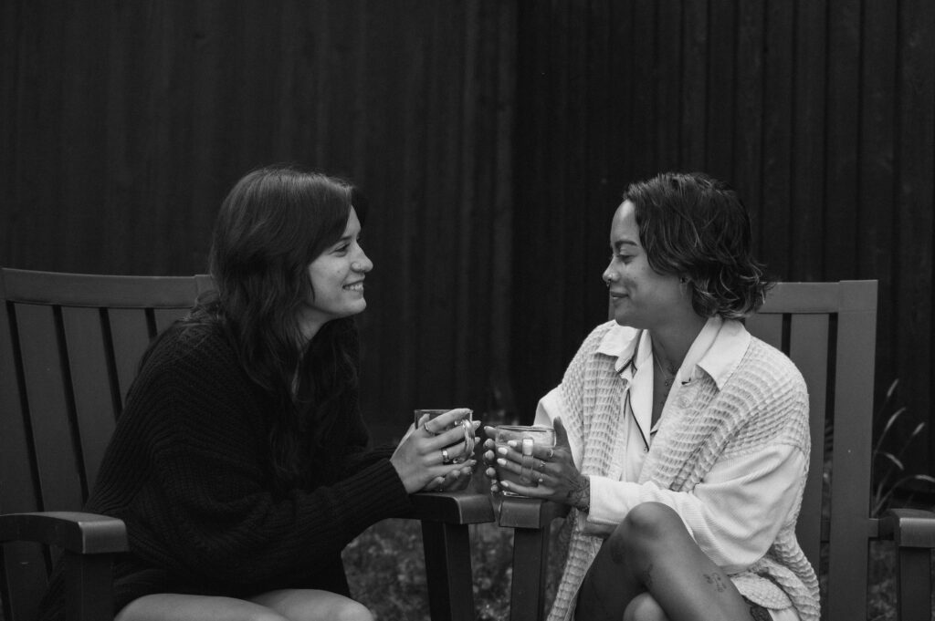 two women enjoying a cup of coffee together outside 