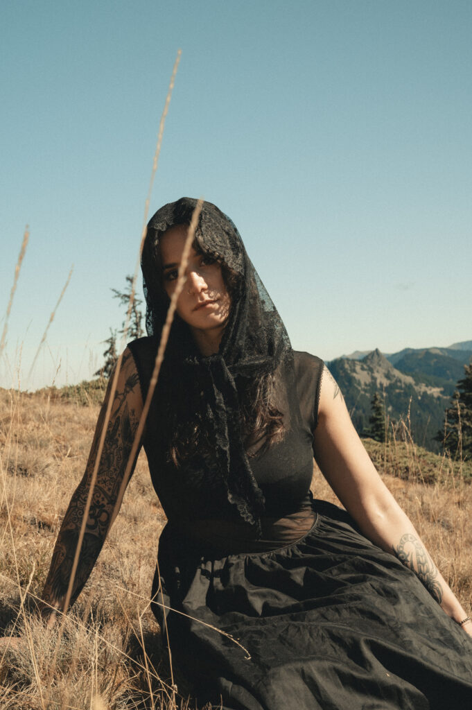 solo portrait of a bride sitting in grass in her black wedding dress