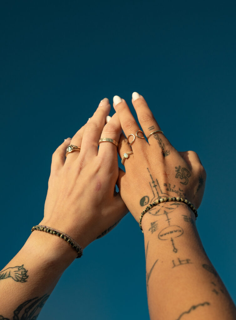 creative detail shot of two women's hands touching with the sky in the back