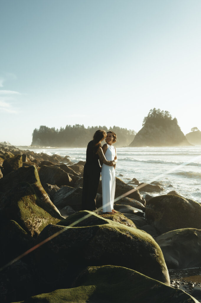 brides standing on the rocks at rialto beach looking out at the ocean