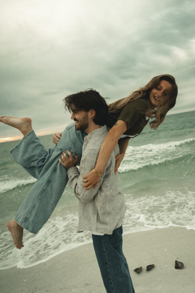 man lifting his girlfriend over his shoulder for creative engagement photo