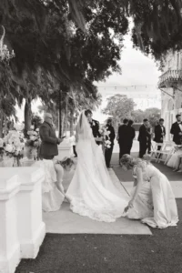 Documentary photo of the maid of honor and mother of the bride fixing the brides dress at the altar