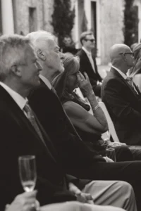 candid shot of the mother of the bride wiping a tear from her eyes during her daughter wedding ceremony