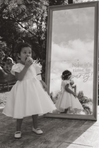 candid photo of a flower girl snacking on an apple after a wedding ceremony